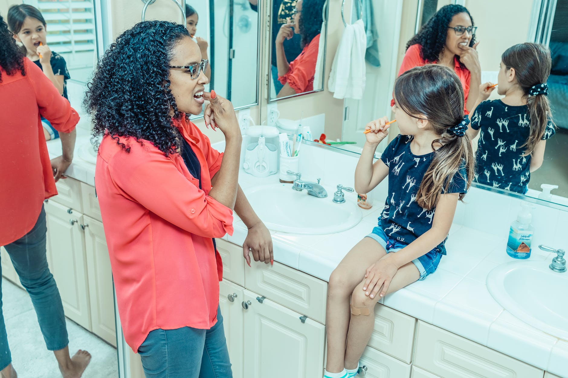 a mother teaching her daughter how to brush her teeth